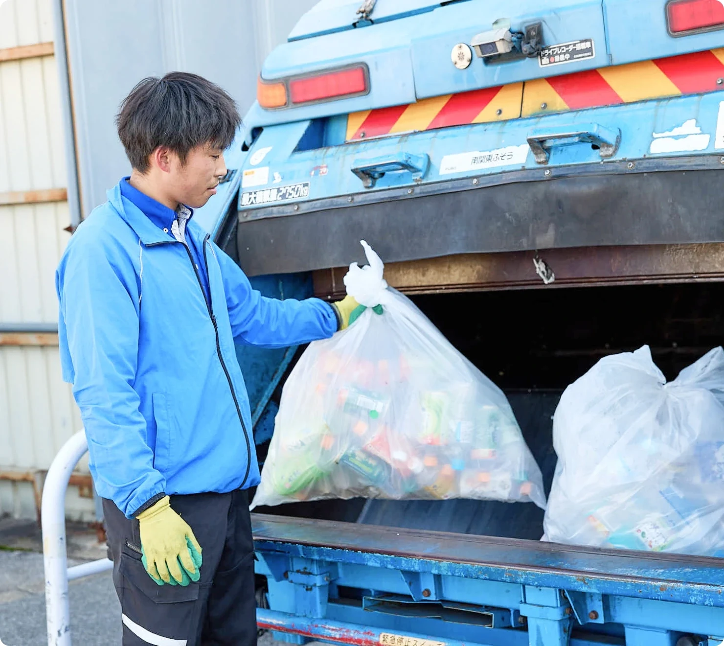 収集車で回収作業を行うスタッフ