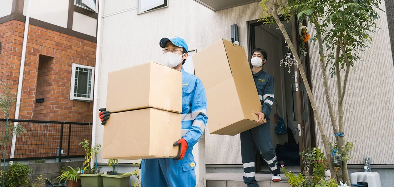 住宅の玄関で引越し荷物を運ぶスタッフ